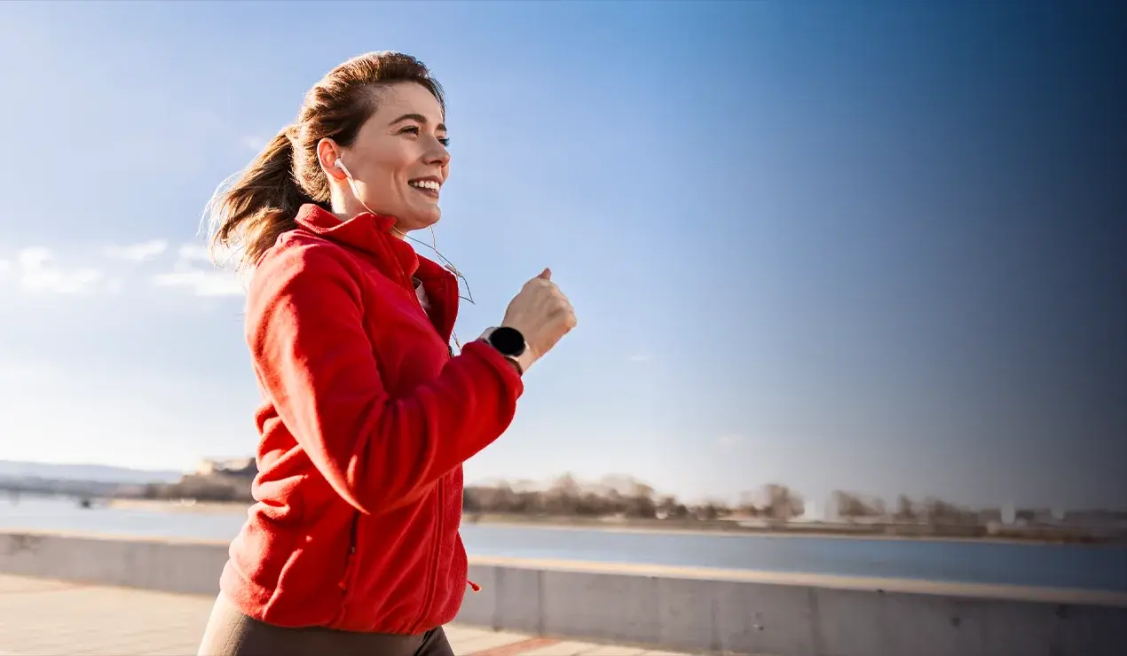Woman running with smart watch and ear buds